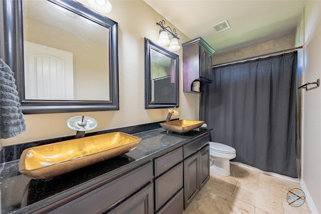 bathroom with tile floors, dual sinks, toilet, and vanity with extensive cabinet space