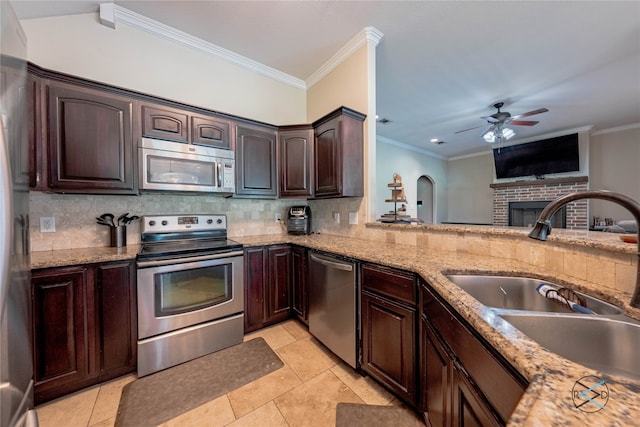 kitchen with light tile floors, appliances with stainless steel finishes, ceiling fan, and a fireplace