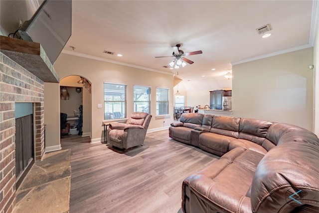 living room with hardwood / wood-style floors, ceiling fan, a fireplace, and crown molding