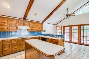 kitchen with stovetop, a kitchen island, light tile patterned flooring, decorative backsplash, and beamed ceiling