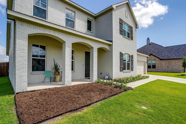 view of front of property featuring a front lawn, a garage, and covered porch