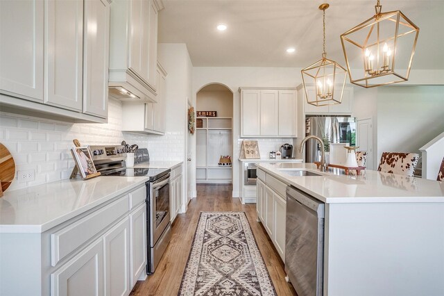 kitchen with hanging light fixtures, appliances with stainless steel finishes, and a center island with sink