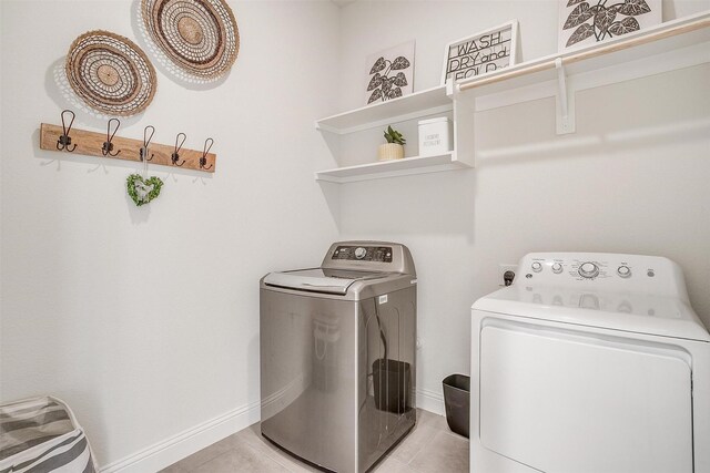 laundry room with light tile patterned floors and washer and clothes dryer