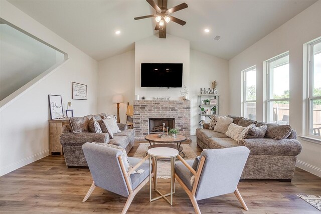 living room with ceiling fan, vaulted ceiling with beams, a brick fireplace, and hardwood / wood-style flooring