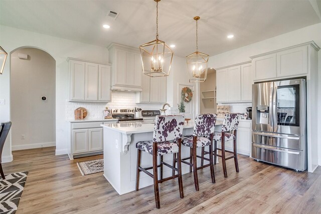 kitchen with appliances with stainless steel finishes, pendant lighting, and white cabinets