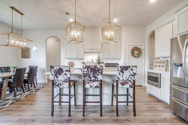 kitchen featuring tasteful backsplash, appliances with stainless steel finishes, white cabinetry, and pendant lighting