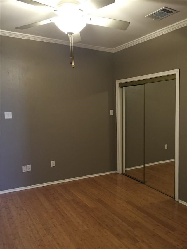 unfurnished bedroom featuring ornamental molding, hardwood / wood-style flooring, ceiling fan, and a closet