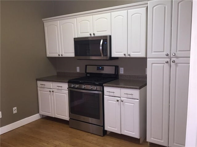 kitchen with white cabinets, appliances with stainless steel finishes, and dark wood-type flooring