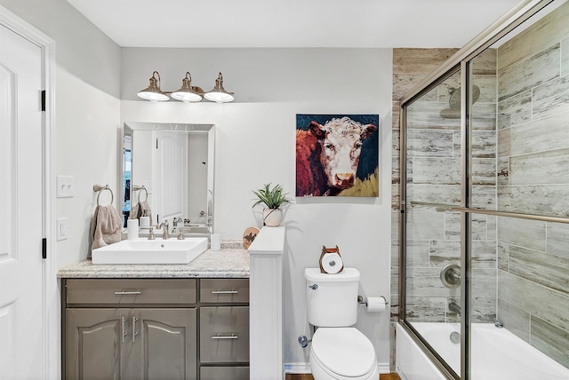 full bathroom featuring enclosed tub / shower combo, vanity, and toilet