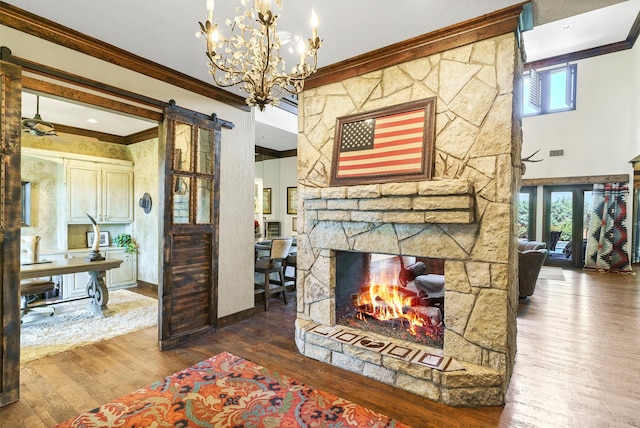 living room with a barn door, a fireplace, ornamental molding, and hardwood / wood-style flooring