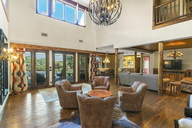 living room with a chandelier, a towering ceiling, and dark hardwood / wood-style floors