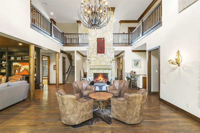 living room featuring dark hardwood / wood-style floors, a chandelier, a high ceiling, and a stone fireplace