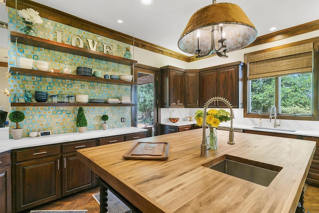 kitchen featuring hanging light fixtures, wooden counters, and sink