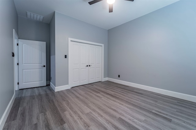 unfurnished bedroom with dark hardwood / wood-style flooring, a closet, and ceiling fan