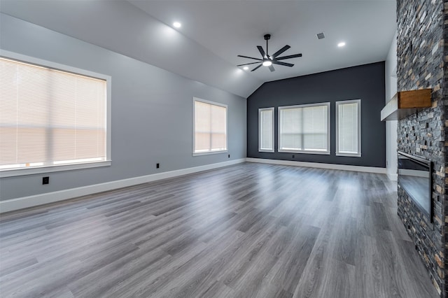 unfurnished living room featuring a stone fireplace, ceiling fan, vaulted ceiling, and wood-type flooring