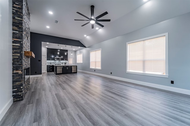 unfurnished living room with ceiling fan, a fireplace, lofted ceiling, and dark wood-type flooring