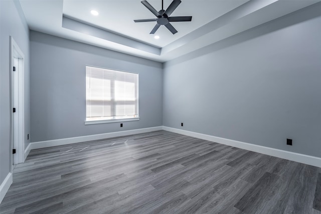 unfurnished room with dark hardwood / wood-style floors, ceiling fan, and a raised ceiling