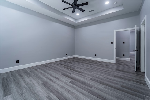 spare room with dark hardwood / wood-style floors, ceiling fan, and a tray ceiling