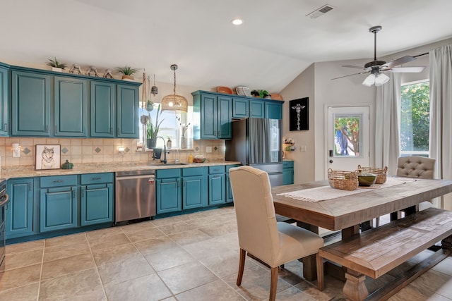 kitchen with lofted ceiling, sink, decorative backsplash, appliances with stainless steel finishes, and decorative light fixtures