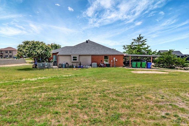 rear view of house featuring a yard, central AC unit, and a carport