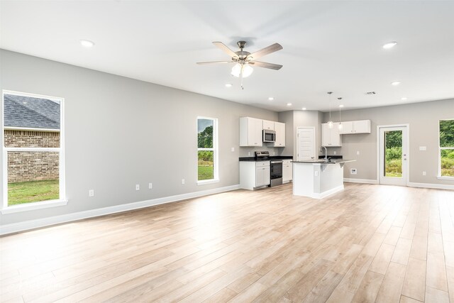 unfurnished living room with plenty of natural light, light hardwood / wood-style flooring, and ceiling fan