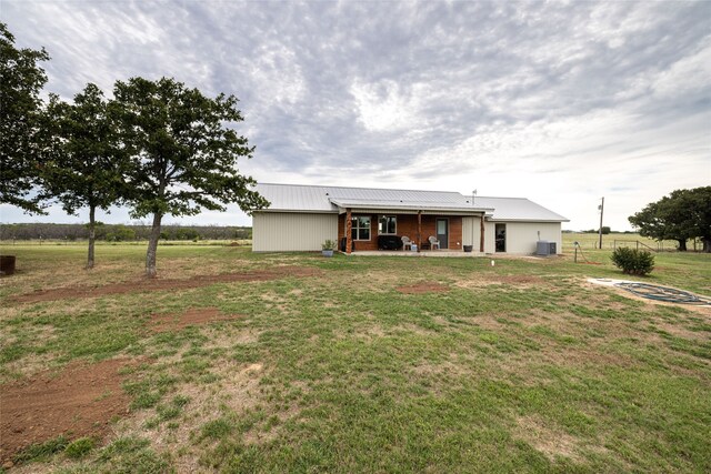 rear view of property featuring a yard and cooling unit