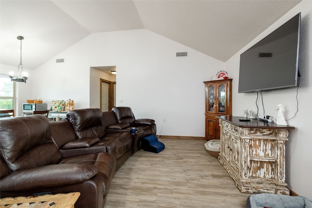 living room with vaulted ceiling, an inviting chandelier, and light hardwood / wood-style flooring