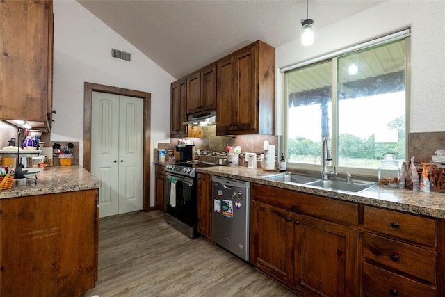 kitchen with lofted ceiling, sink, light hardwood / wood-style floors, appliances with stainless steel finishes, and backsplash