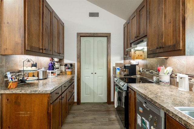 kitchen featuring lofted ceiling, backsplash, stainless steel appliances, and light hardwood / wood-style flooring