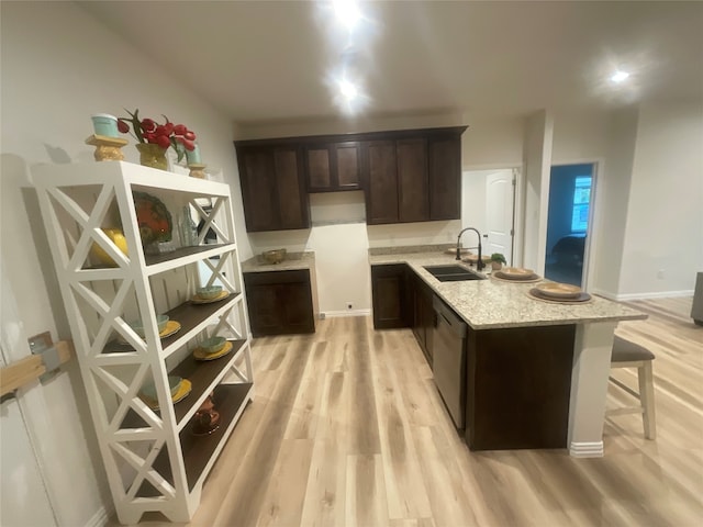 kitchen featuring light stone countertops, light hardwood / wood-style flooring, dark brown cabinetry, sink, and a kitchen bar