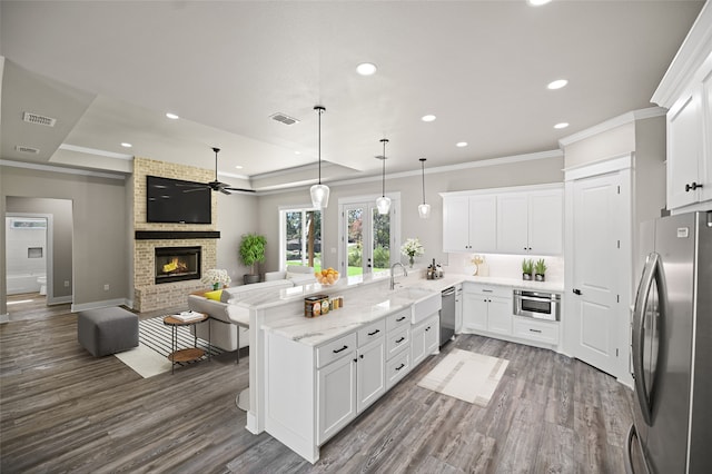 kitchen with kitchen peninsula, appliances with stainless steel finishes, dark wood-type flooring, pendant lighting, and white cabinets