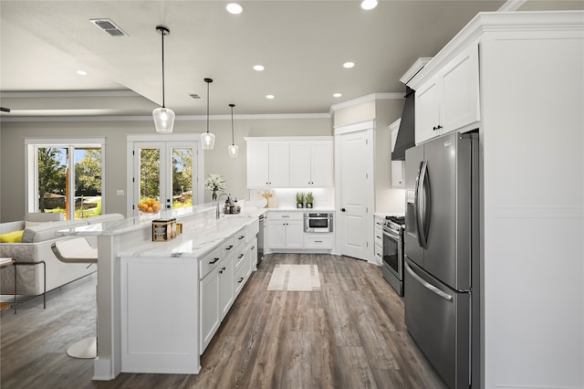 kitchen with decorative light fixtures, a kitchen bar, white cabinetry, and appliances with stainless steel finishes