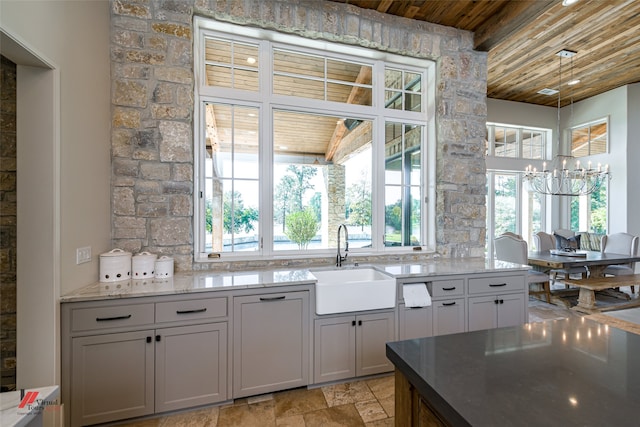 kitchen with wood ceiling, sink, light tile patterned floors, light stone countertops, and a chandelier