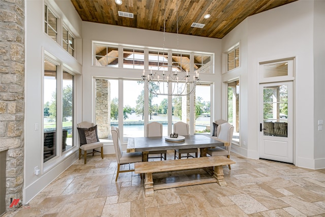 tiled dining space featuring an inviting chandelier, a towering ceiling, and wood ceiling