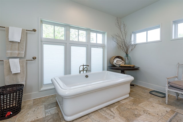 bathroom featuring plenty of natural light, tile patterned flooring, and a tub to relax in