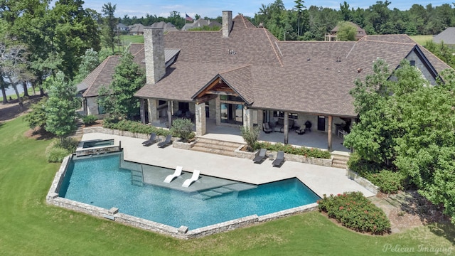 rear view of property with a patio area, a pool with hot tub, and a yard