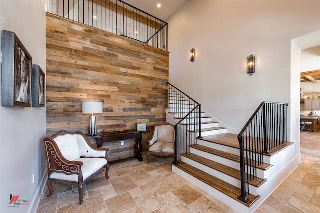 stairs with light tile patterned floors, wooden walls, and a high ceiling