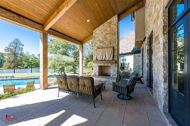 view of patio / terrace featuring an outdoor living space with a fireplace, a water view, and a fenced in pool