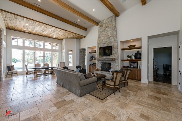 living room featuring a stone fireplace, light tile patterned floors, built in shelves, beam ceiling, and a towering ceiling