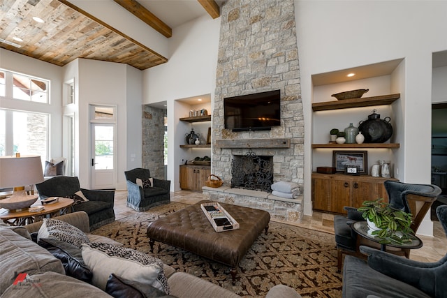 living room featuring built in features, beamed ceiling, a stone fireplace, a high ceiling, and light tile patterned flooring