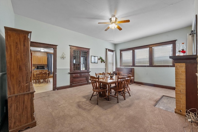 dining space with ceiling fan and light carpet