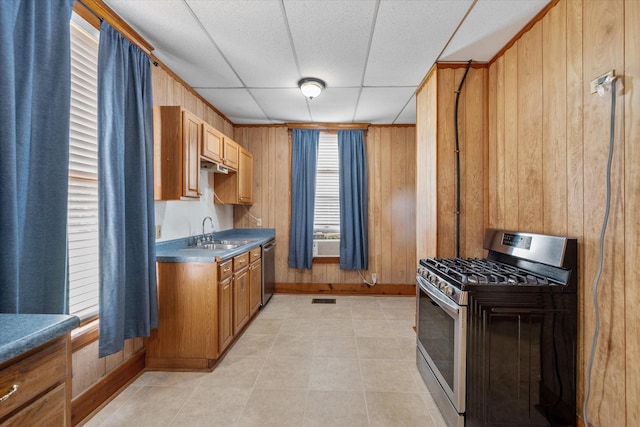 kitchen featuring wood walls, sink, stainless steel appliances, and a drop ceiling