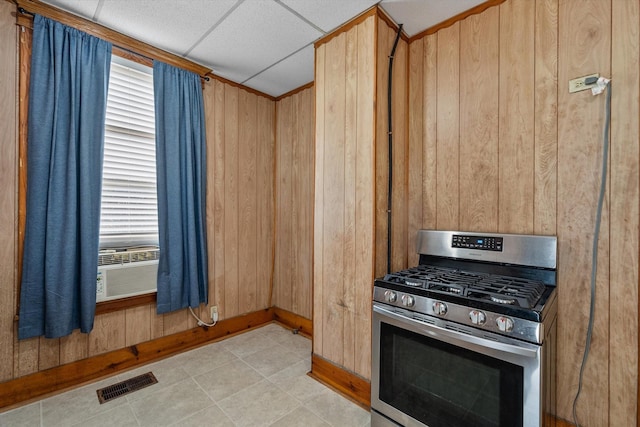 kitchen featuring gas stove, cooling unit, a paneled ceiling, wooden walls, and light brown cabinetry