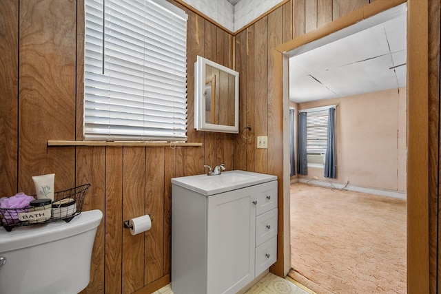 bathroom with vanity, toilet, and wooden walls