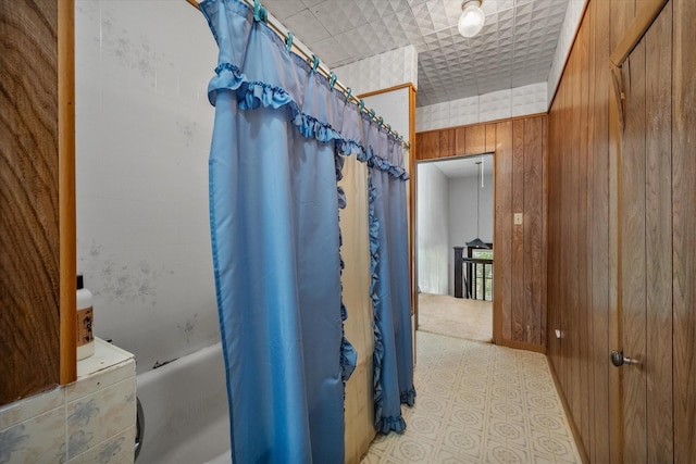 bathroom featuring shower / bathtub combination with curtain and wood walls