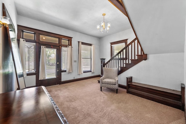 carpeted entryway with a chandelier