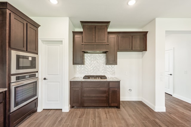 kitchen featuring dark brown cabinetry, appliances with stainless steel finishes, and light wood-type flooring