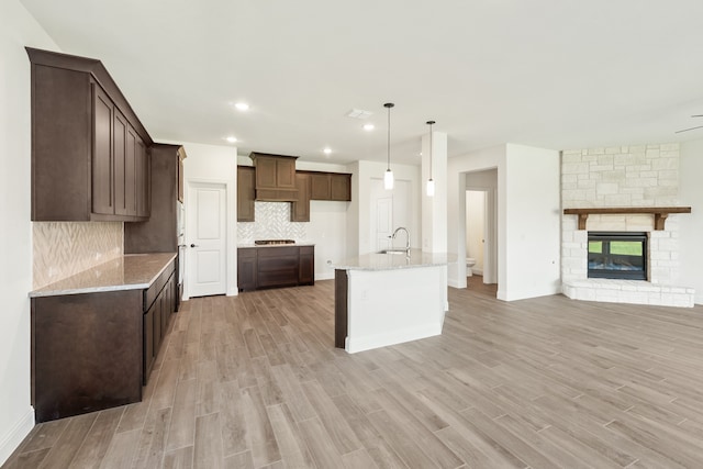 kitchen featuring light stone countertops, light wood-type flooring, sink, and decorative light fixtures