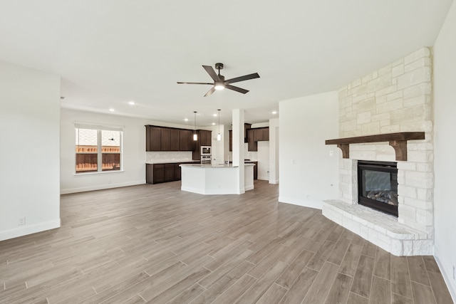 unfurnished living room featuring ceiling fan, a fireplace, and light hardwood / wood-style floors