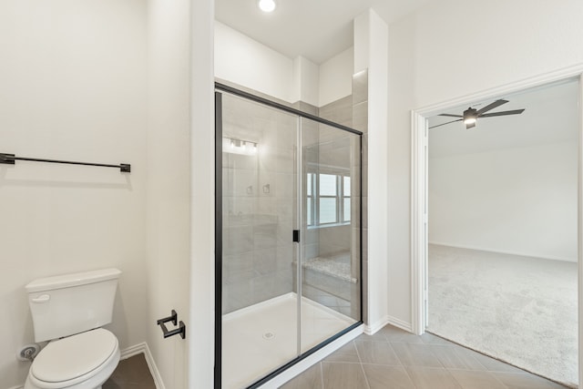 bathroom featuring tile patterned flooring, ceiling fan, a shower with door, and toilet